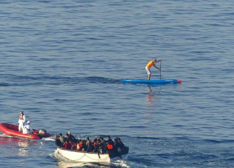 Kontraster: En turist passerer migrantbåten på paddle board, i det den er på vei inn mot Arguineguín. Foto: Jånn Normann