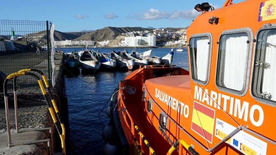 Arkivfoto av en redningsbåt med migrantbåter i bakgrunnen, i Arguineguín på Gran Canaria. Foto: Canary4stock/Shutterstock