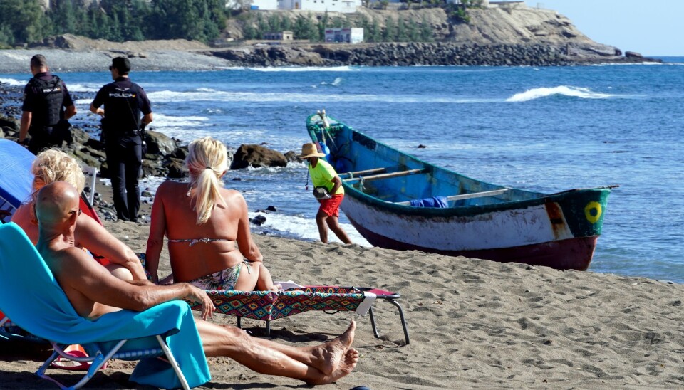 KONTRASTER: Mens turistene soler seg, ligger en forlatt migrantbåt igjen på stranda sør på Gran Canaria.