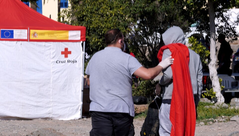 En migrant får følge til Røde Kors sitt telt etter ankomst ved El Perchel-stranda sør på Gran Canaria.