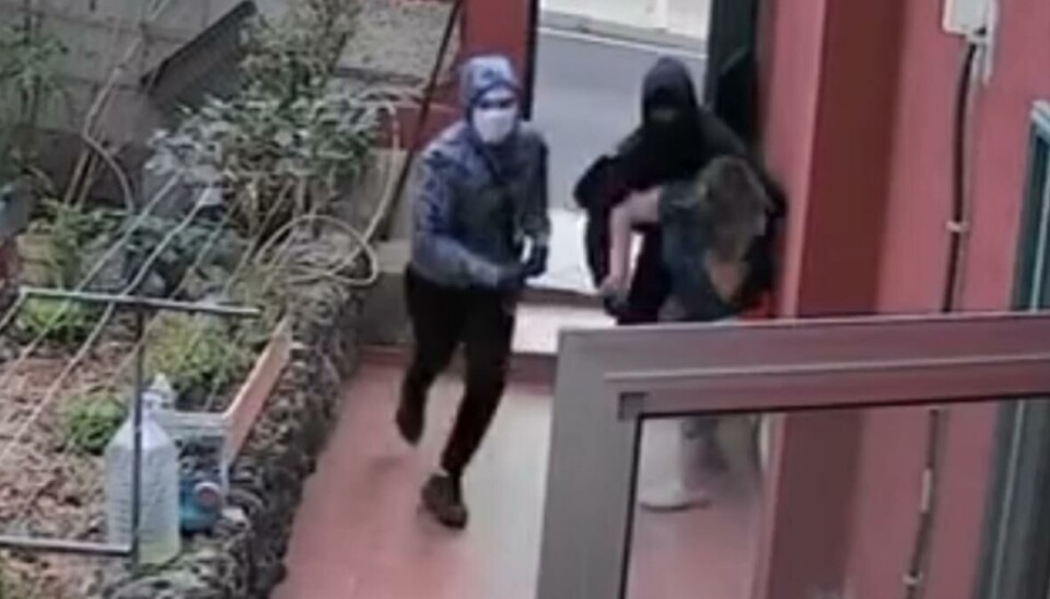Overvåkningsbilder fra et kamera viser de maskerte mennene i det de overfaller kvinnen.